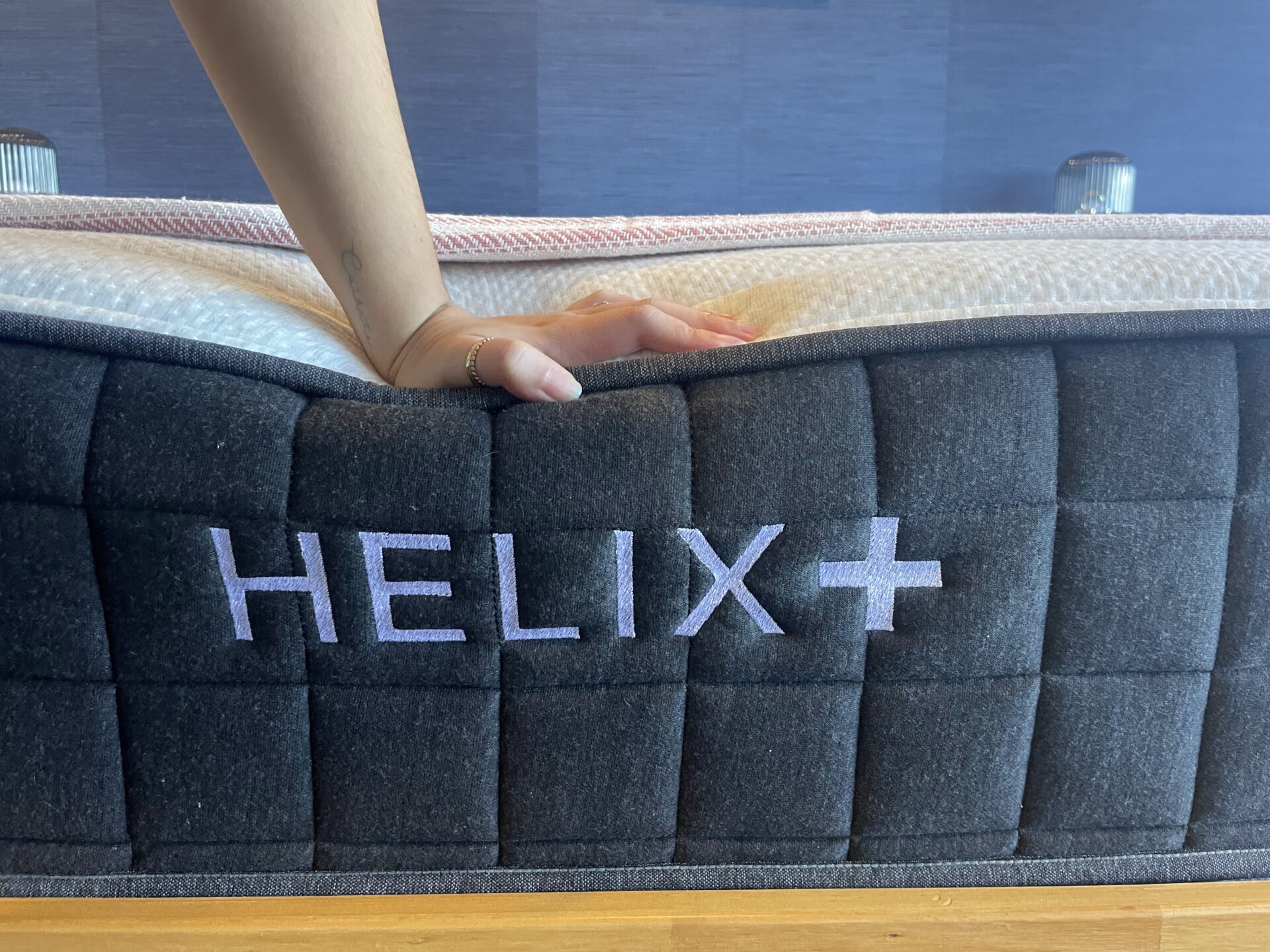 White woman’s hand pressing the edge of a Helix Plus mattress