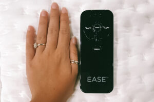 The Sealy Ease remote placed next to a hand for a size comparison